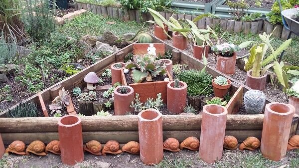 Old terracotta pipes, sandpit timbers and clay snails create a cactus display