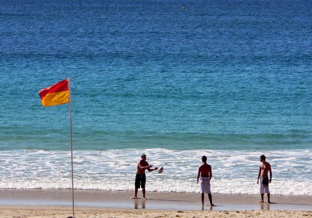 tips on how to stay water safe at Australian beaches this summer. Photo of friends playing with a ball on a beach.