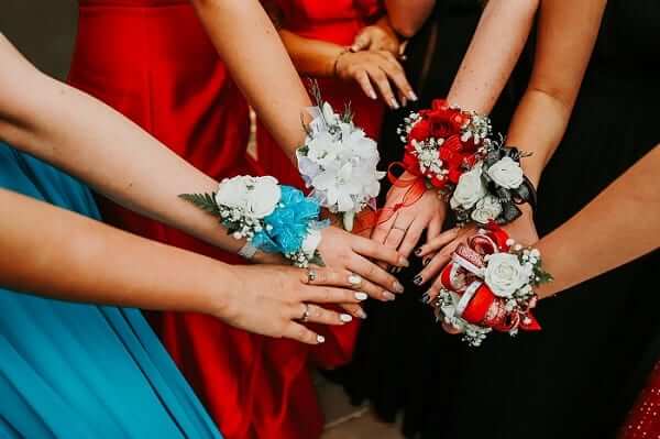 Year 12 formals being canceleld reflects poorly on education system. A group of girls with corsages putting their hands together in a circle. 