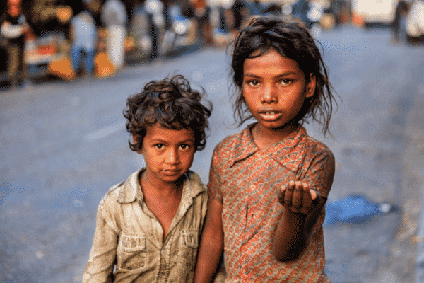 two poor indian children stand on the street