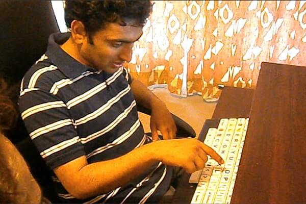 Sidharth Chandran is typing on his keyboard. It is a AAC keyboard, and the letters are big.