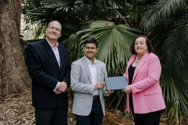 A student receives an award from two UOW dignitaries.