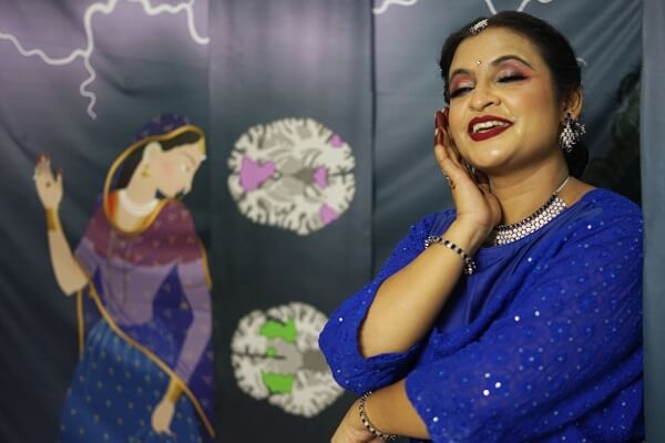 Priyanka Jain dressed in traditional Kathak clothing performs in front of a set with images of a brain. 