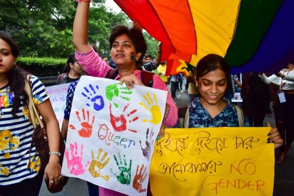 Two queer folks hold placards celebrating their identities at Kolkata's 2018 victory march. 
