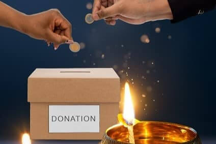 People putting coins in a donation box for Diwali