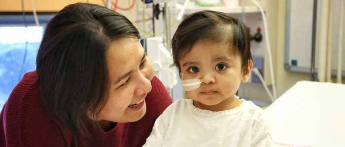 A boy in a hospital with a tube in his nose looks at the camera. 