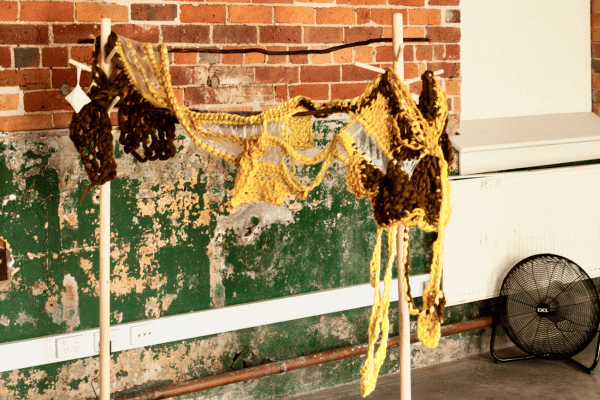 a brown and yellow embroidered piece hangs near a wall. 