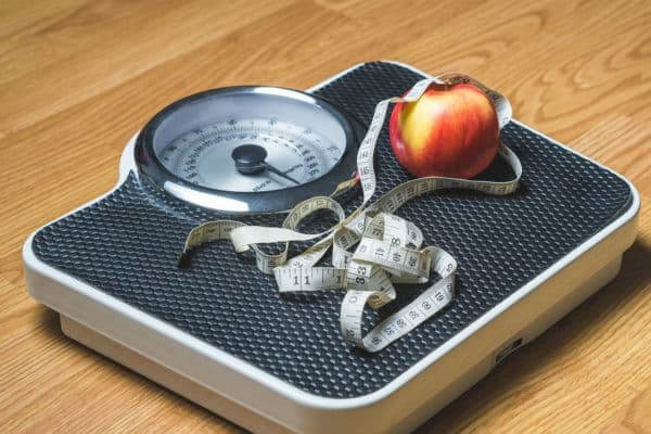 An apple and measuring tape on a weight 